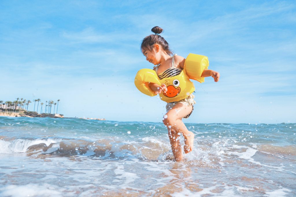 child in floaties on beach, summer toys for kids