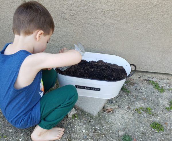 child watering seeds, raising kids to be earth conscious