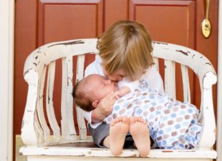 big brother holding a newborn baby on a bench