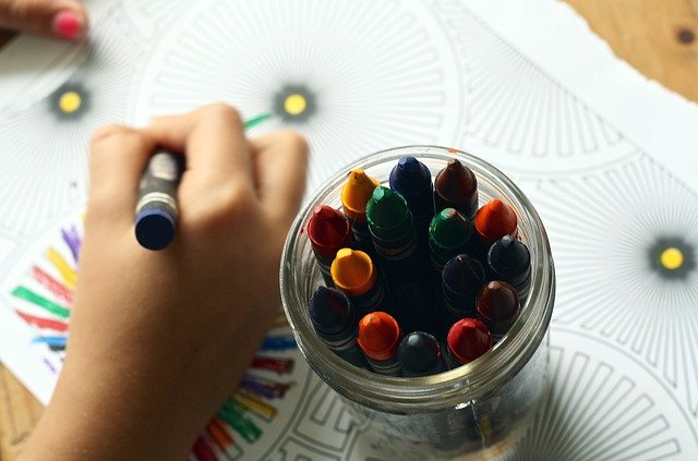 jar of crayons next to child's hand, ways to simplify your life