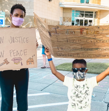 black mom and black child holding protest signs