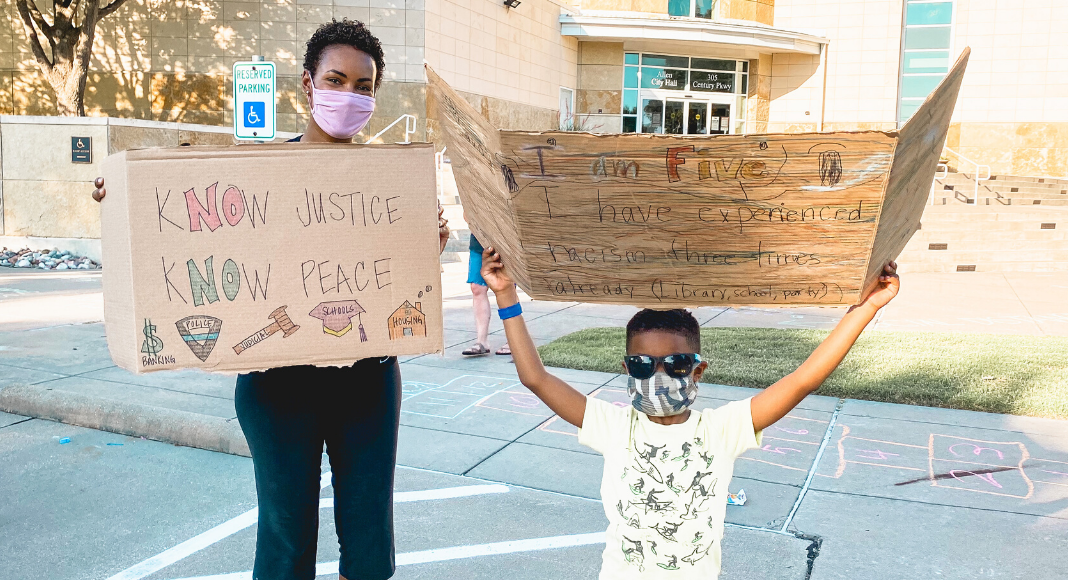 black mom and black child holding protest signs