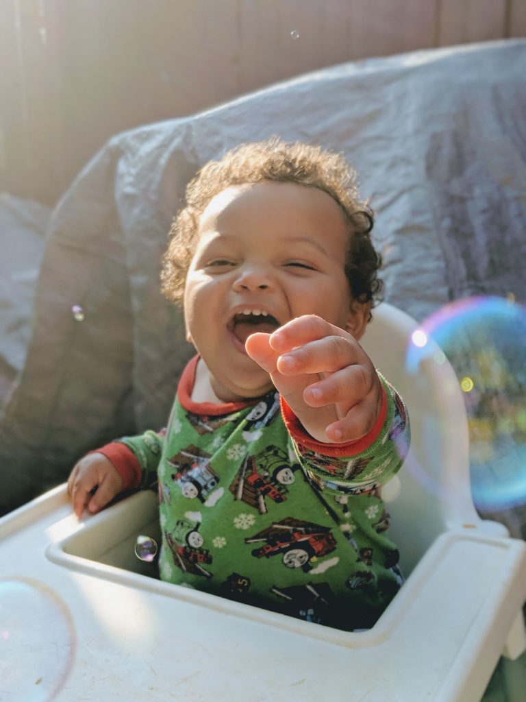 child in highchair reaching for bubbles, summer photo prompts