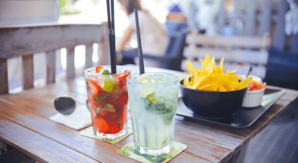 Cocktails, chips, and salsa served outside on a patio table at a restaurant.
