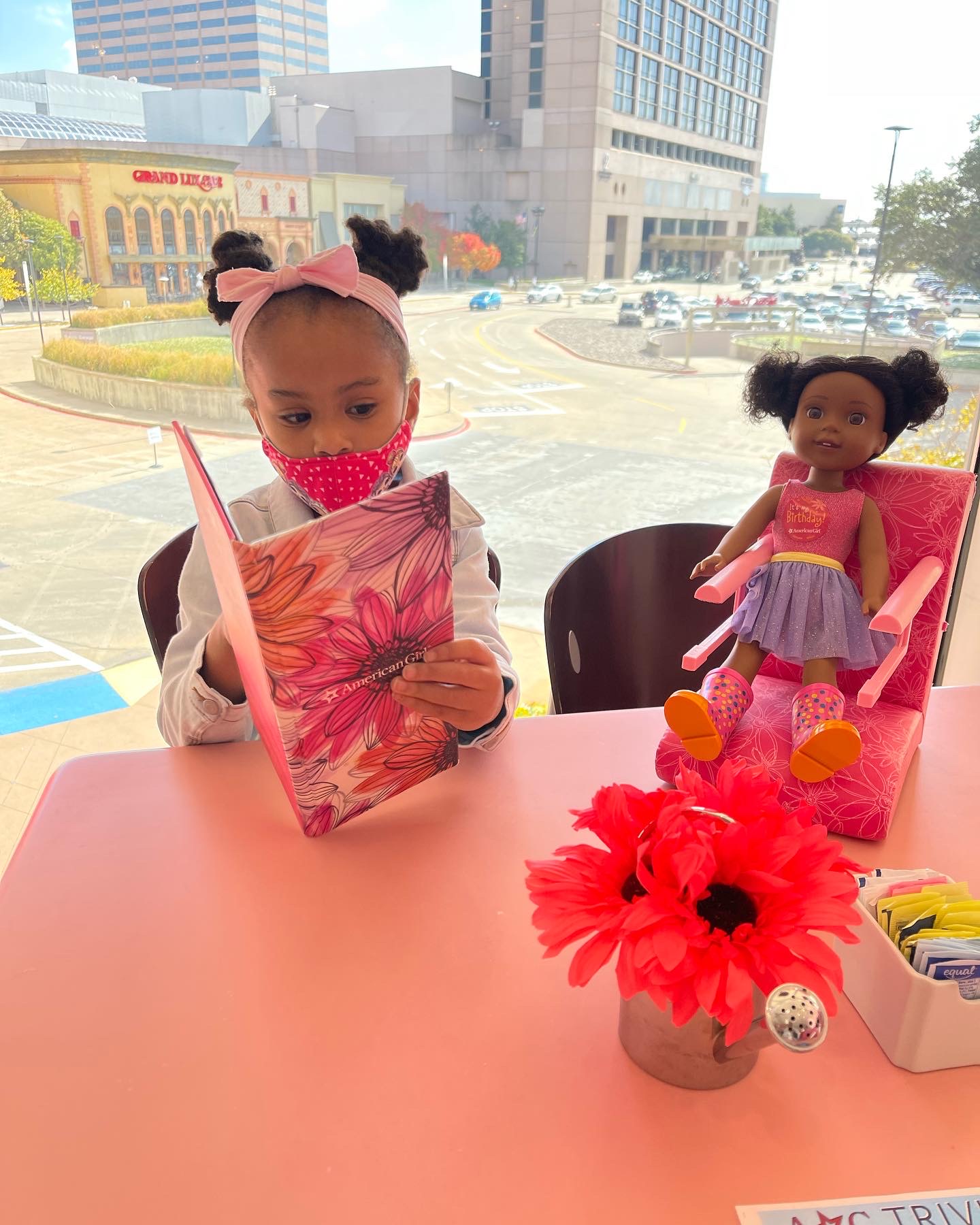 child reading menu with doll seated next to her at the American Girl Store Bistro in Dallas
