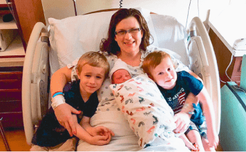mom with newborn and children in hospital bed