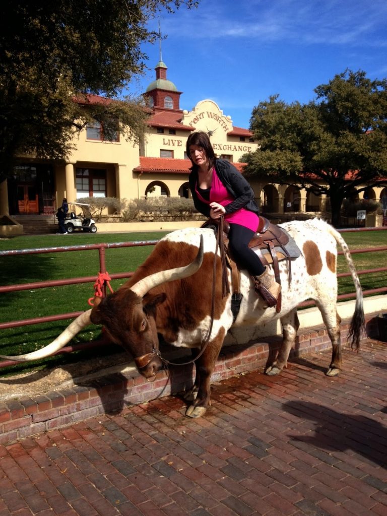 woman sitting on a longhorn at the Ft. Worth Stockyards, DFW Staycations