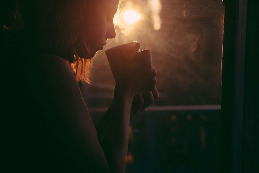 woman sipping mug by the fire, how to beat the winter blues