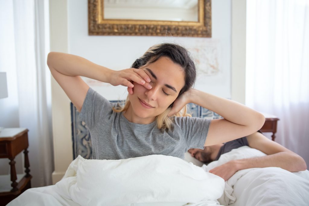 woman waking up with a stretch, the benefits of being an early riser