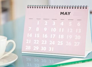 A tabletop with coffee mug and calendar flipped to May