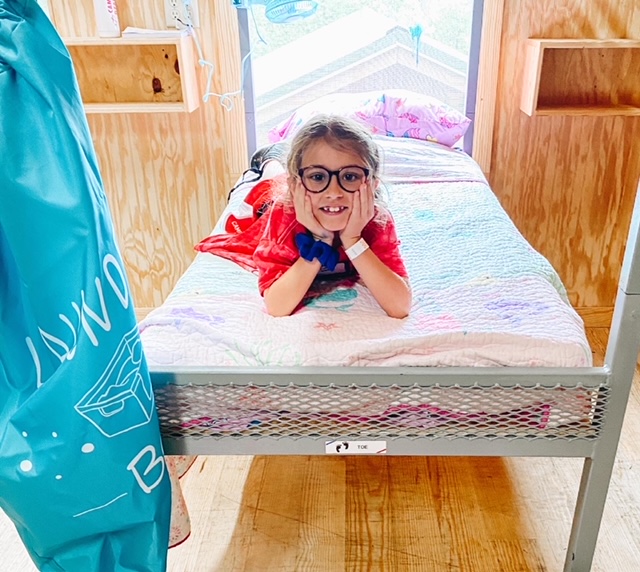 girl on camp bunk bed, overnight camp must-haves