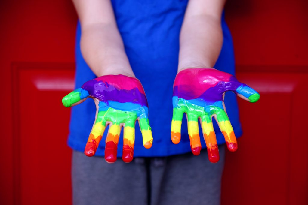 child with rainbow paint on hands, family Pride events in Dallas