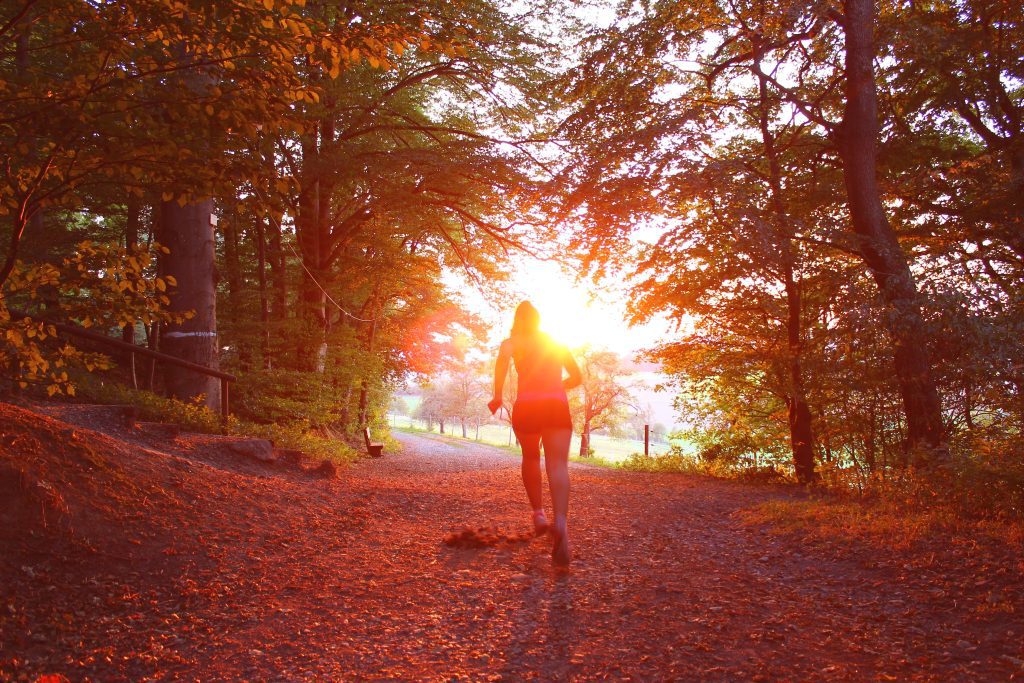 woman jogging on trail in sunset
