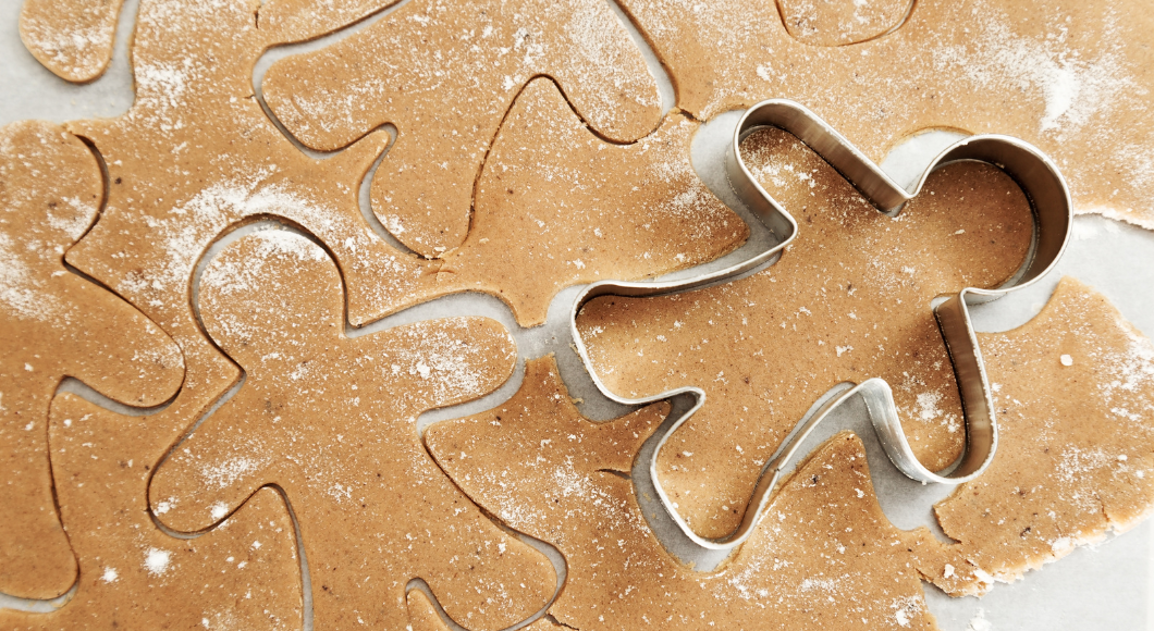 A gingerbread man cookie cutter on top of a batch of dough.