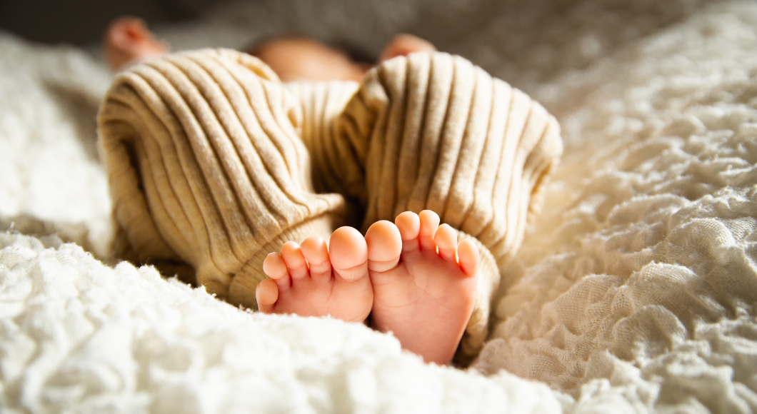 Close up on feet of baby laying on a fluffy pad