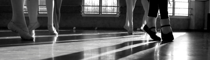 black and white image of ballet-slipper clad feet in a ballet class