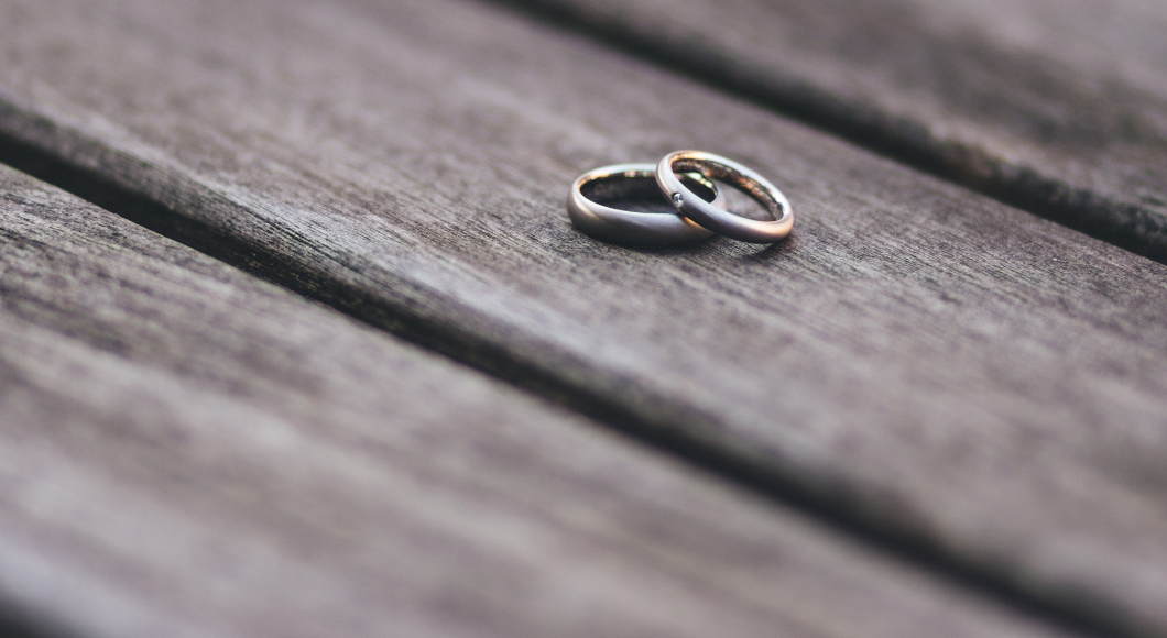 Two wedding rings lay on a piece of wood.
