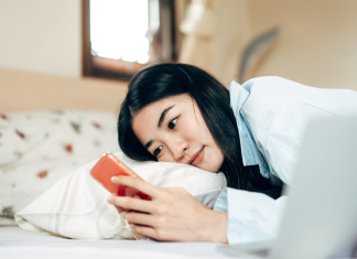 A woman in bed looking at her phone.