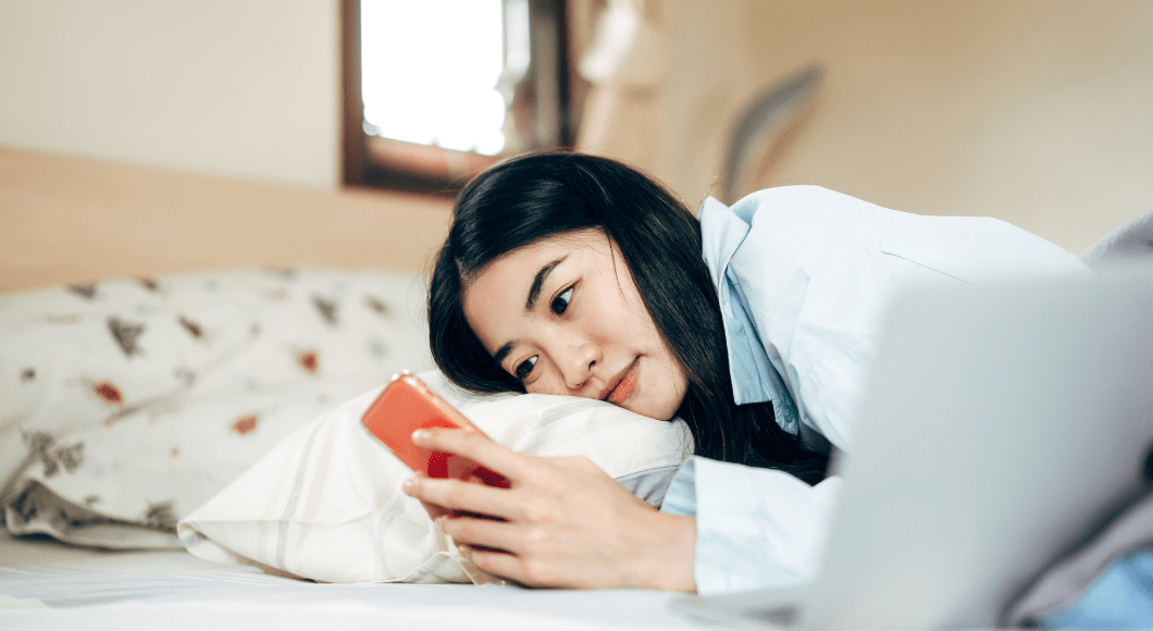 A woman in bed looking at her phone.