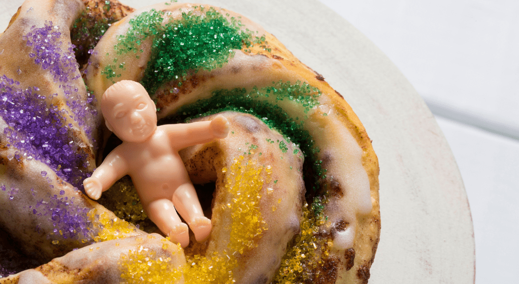 A toy baby rests on top of a king cake.