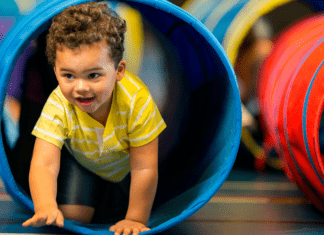 A toddler boy crawls through a tube.