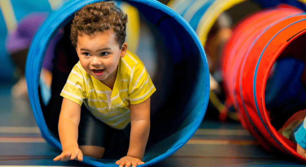 A toddler boy crawls through a tube.