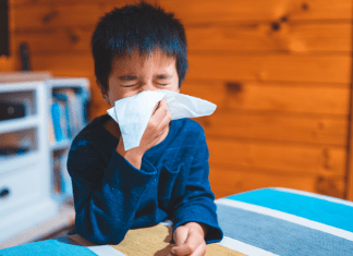 A boy blows his nose into a tissue.