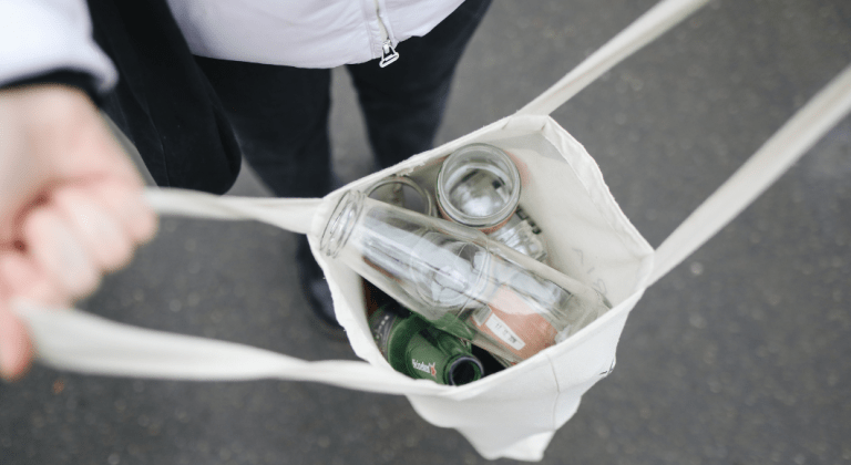 A canvas tote filled with glass bottles.