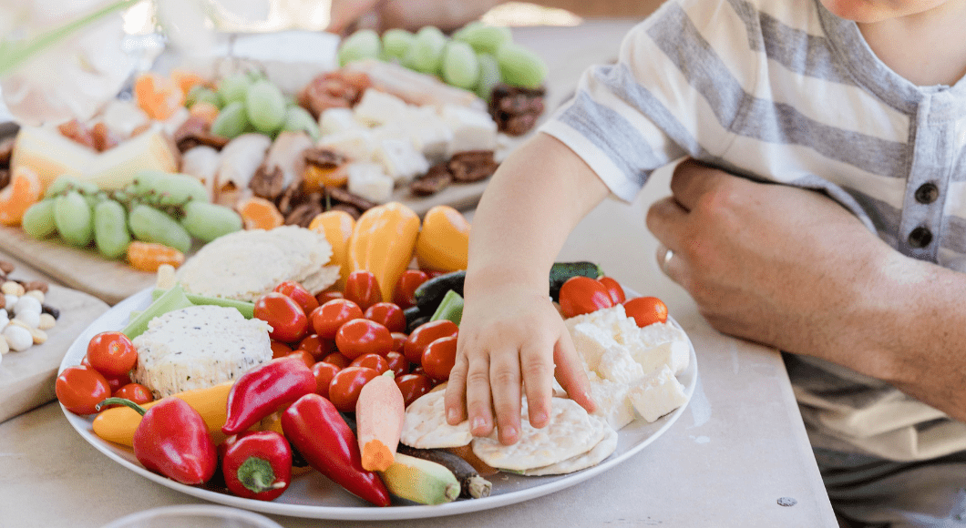 Child reaching out to grab healthy food
