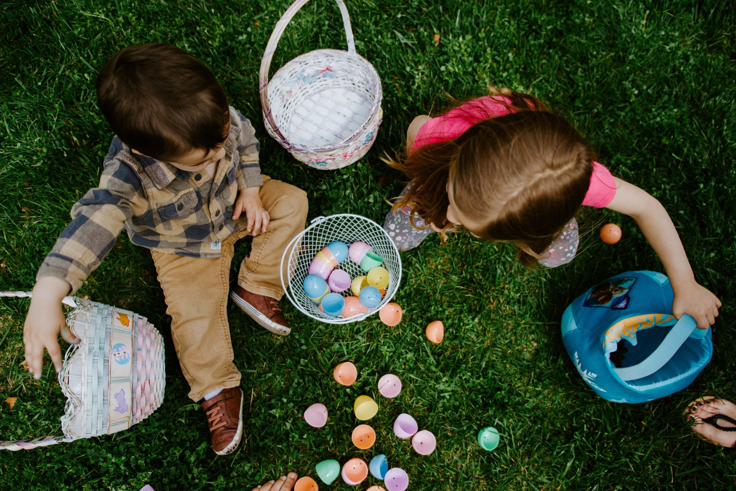 Kids sit in the grass with Easter items