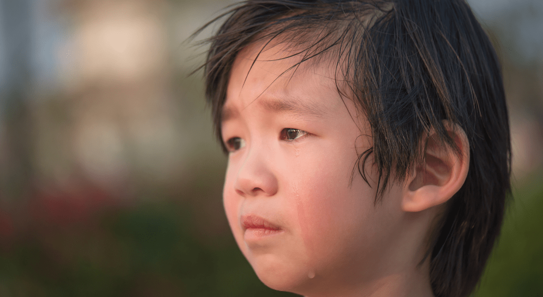 A young boy is sad with tears running down his cheek.