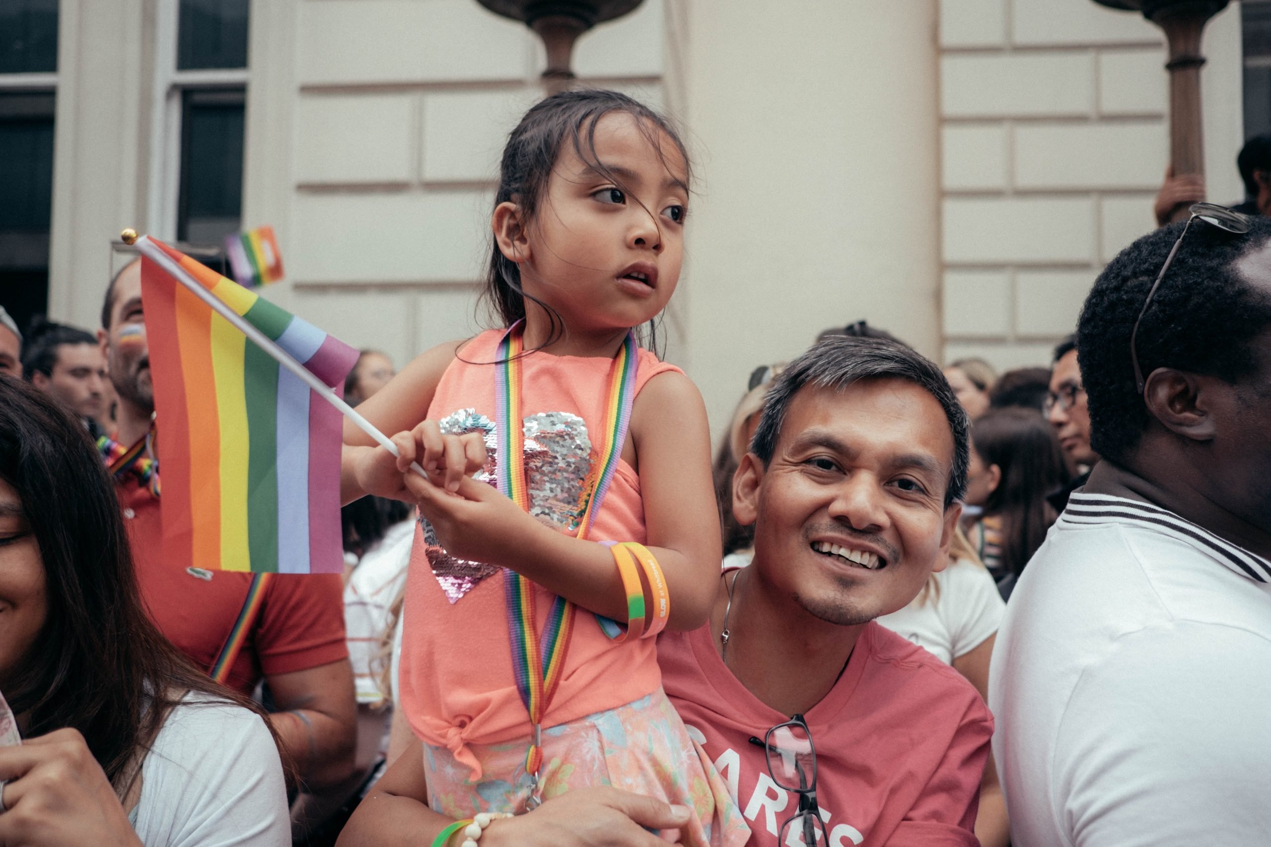 child on parent's shoulder at pride parade