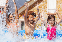 Three kids splash in a pool outside.