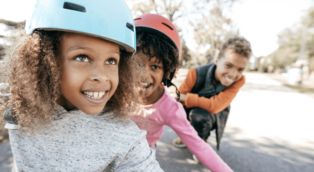 Kids smile and wear bike helmets.