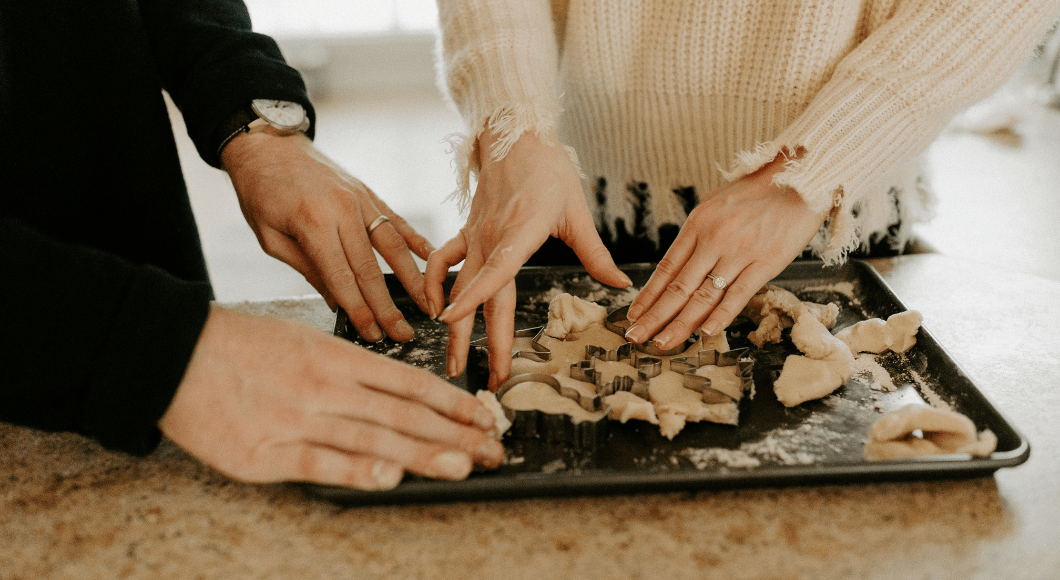 Couple cutting out cookie dough.
