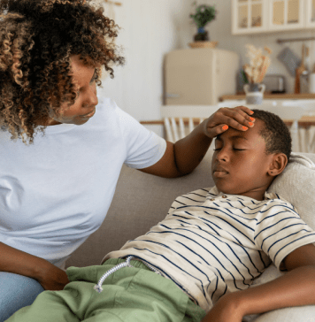 A mom feels her son's forehead to check his temperature.