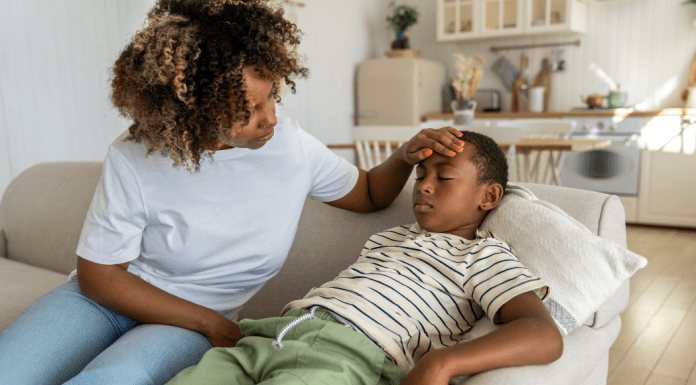 A mom feels her son's forehead to check his temperature.