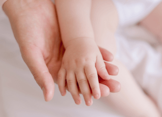 A baby rests her hand in mom's palm.