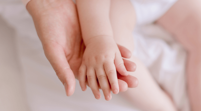 A baby rests her hand in mom's palm.