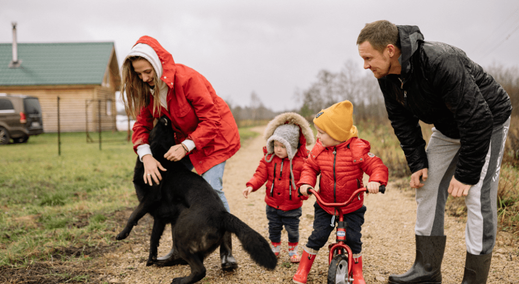 A family of four is bundled up enjoy outdoors with dog.