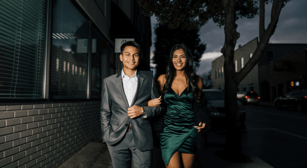 Prom dates dressed to the nines walk arm in arm.