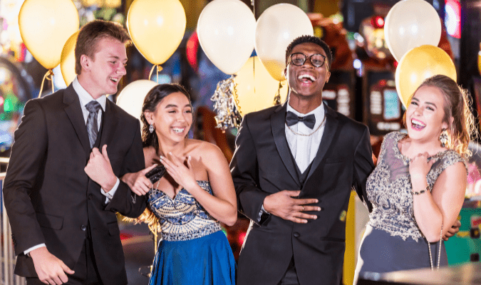 Young men and ladies are all dressed up in their formal attire for prom.