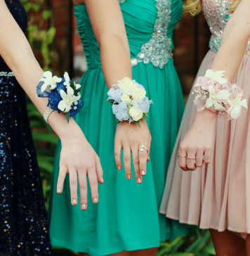 Trio of girls show off prom corsages on their wrists.