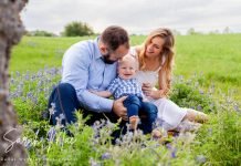 Family sits for a portrait in a patch of Texas bluebonnets.