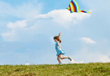 Child runs and flies a kite.