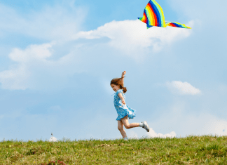 Child runs and flies a kite.