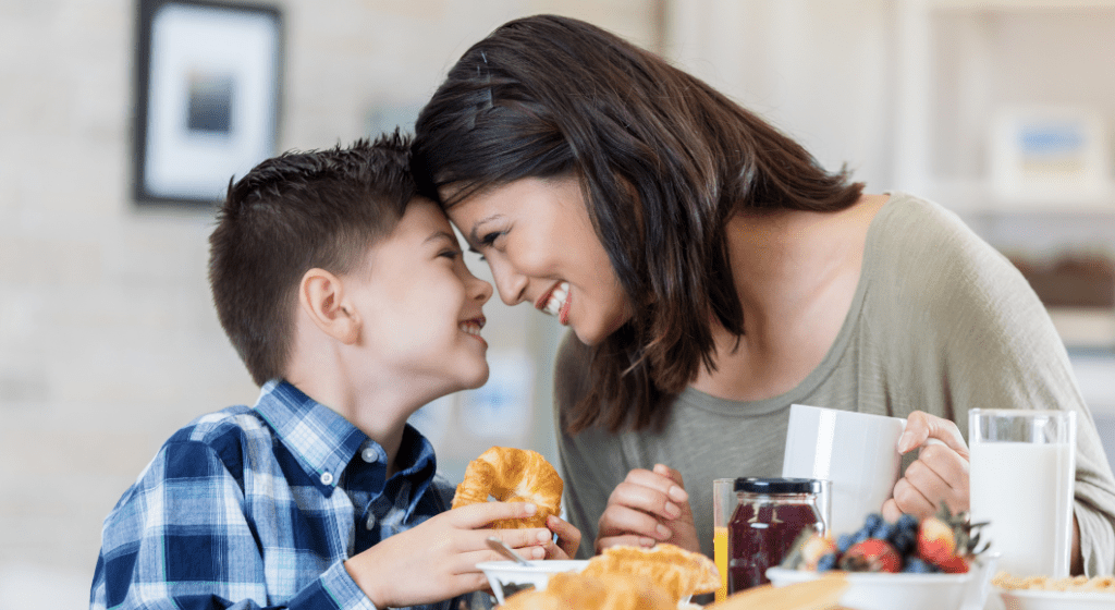 Mom and son touch foreheads for a tender moment while eating brunch together.