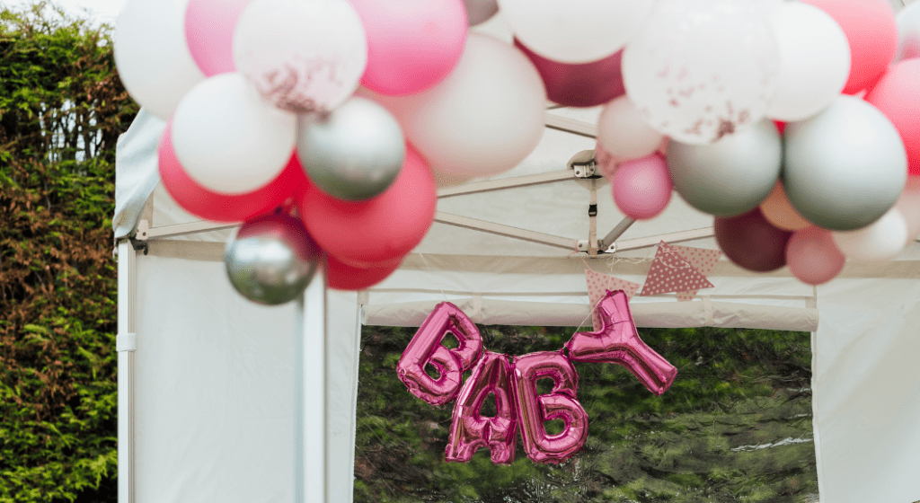 Balloons spell "BABY," and hang in an outdoor canopy for a baby shower.