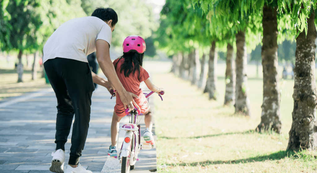 Dad teaches daughter to ride a bike.
